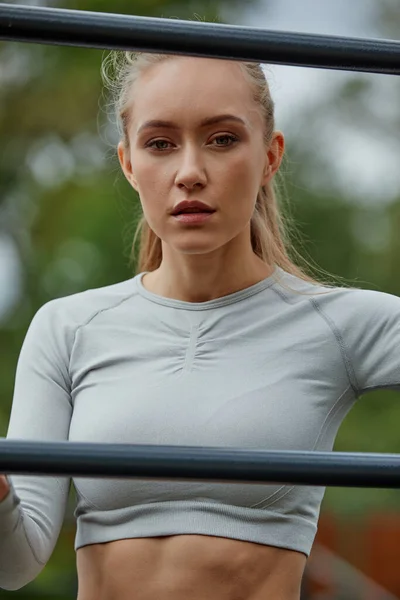 Estilo de vida activo. Mujer rubia delgada haciendo ejercicio en el gimnasio al aire libre en verano día cálido. — Foto de Stock