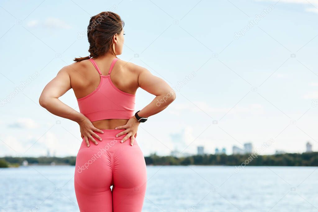 Young beautiful woman with a slim figure goes in for sports at beach. Fitness, sport and healthy lifestyle concept. Rear view