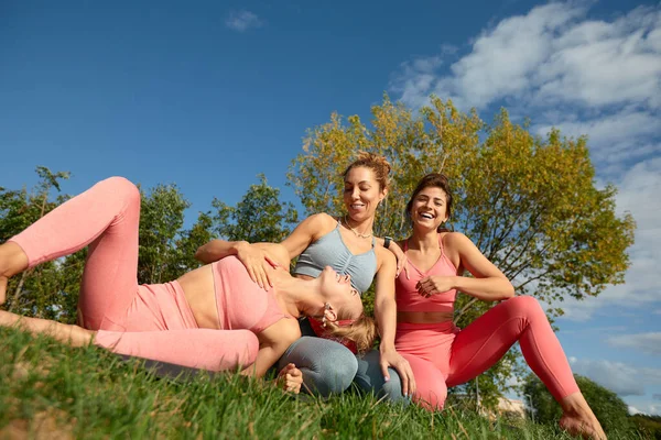 Lächelnde Fitness-Frauen in Trainingsanzügen unterhalten sich auf einer Straße. Drei Joggerinnen stehen beim morgendlichen Joggen auf einer Straße — Stockfoto