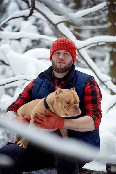 Счастливый человек держит в руках прекрасную собаку в снежном лесу. Улыбающийся мальчик обнимает очаровательного щенка в зимнем лесу. Любитель домашних животных. Dog - human 's friend concept. — стоковое фото