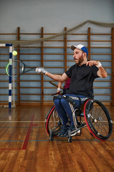 휠체어를 타고 법정에서 테니스를 치는 청년. 뱀장어 의자 공 테니스. — 스톡 사진