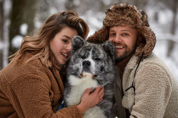 Casado jovem casal em um passeio na floresta de inverno com um cão de estimação husky — Fotografia de Stock