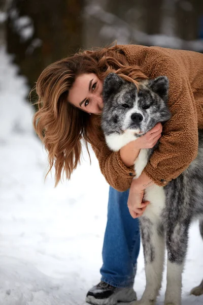 Love to the animals. Young woman playing in the snow with a husky dog. Pet lover. Dog - human s friend concept. — 图库照片