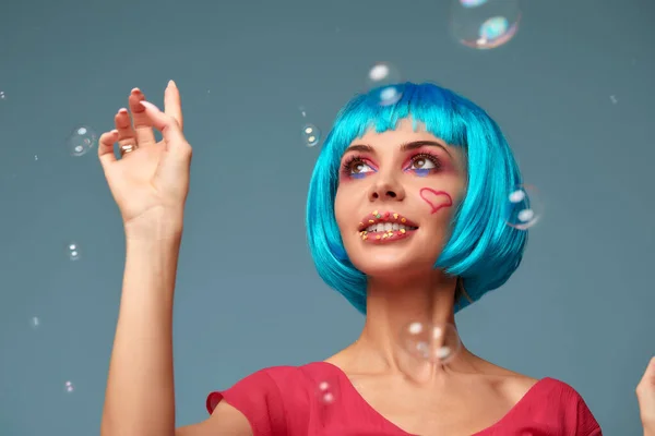 Красива молода жінка з блакитною перукою і яскравим макіяжем в мильних бульбашках. Модна модель дівчини з креативним кольоровим макіяжем. Жіноча концепція ляльок . — стокове фото