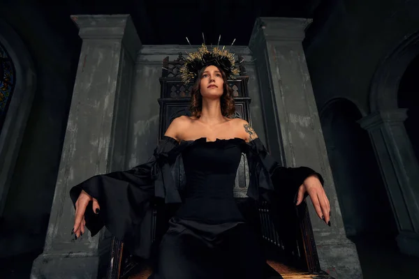 Portrait d'une belle jeune femme médiévale en robe noire en couronne élégante assise sur un trône. L'histoire du Moyen Âge — Photo