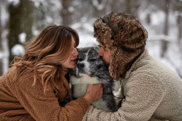年轻夫妇笑着和他们的哈士奇狗在冬季公园里玩得很开心 — 图库照片