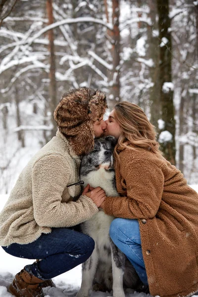 Jovem casal sorrindo e se divertindo no parque de inverno com seu cão husky — Fotografia de Stock