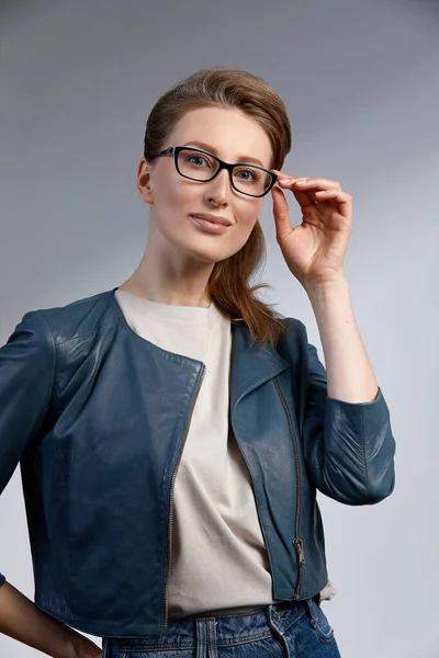 Красивая молодая кавказская студия бизнесвумен снималась на сером фоне. Очаровательная и уверенная в себе серьезная блондинка в тёмно-синем пиджаке в очках — стоковое фото