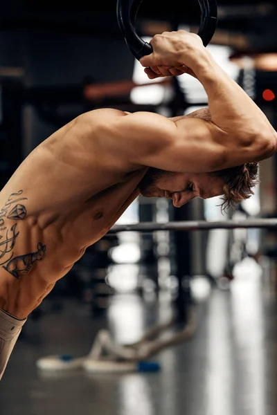 体操リングにジムでワークアウトに合わせてやって強烈な若い男を越える筋肉アップ運動 — ストック写真