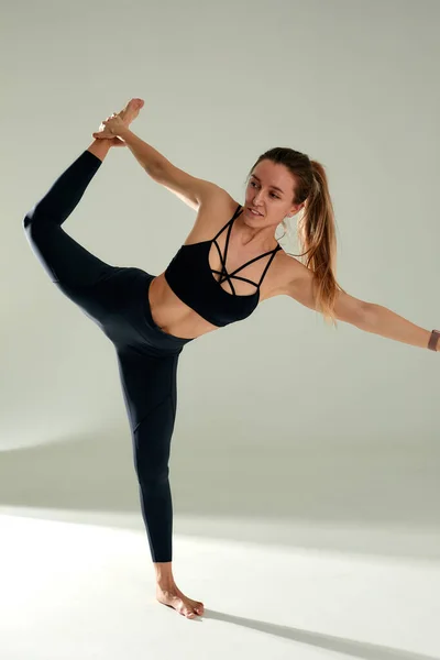 身材矮小的年轻女子在白种人背景下进行瑜伽练习 健康生活的概念以及身体和精神发育之间的自然平衡 — 图库照片
