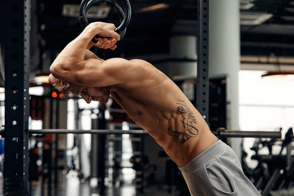 М'язисті вправи молодий чоловік робить інтенсивний хрест підходить тренування в спортзалі на гімнастичних кільцях . — стокове фото