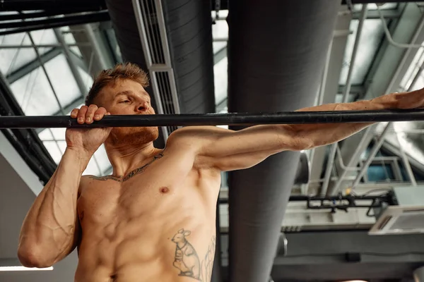 Μυώδης ισχυρός άνδρας άσκηση στο αθλητικό γυμναστήριο, Ο άνθρωπος κάνει οριζόντιες push-ups με μπαρ στο γυμναστήριο. Γυμναστήριο με χώρο αντιγραφής. — Φωτογραφία Αρχείου