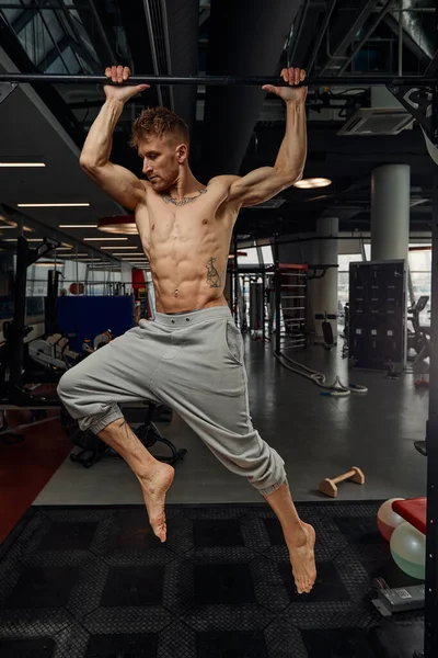 Muskulöser starker Mann, der in der Sporthalle trainiert, Mann, der horizontale Liegestütze mit Stangen in der Turnhalle macht. Hintergrund Turnhalle mit Kopierraum. — Stockfoto