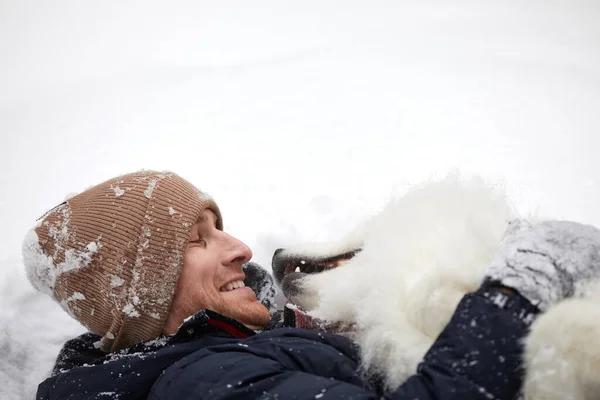 人間と犬は親友です。晴れた日には深い雪の中で冬の雪の森の中を歩く男と犬. — ストック写真