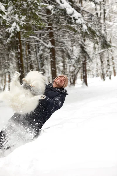 Um humano e um cão são os melhores amigos. Homem e cão caminham na floresta nevada no inverno na neve profunda em um dia ensolarado. — Fotografia de Stock