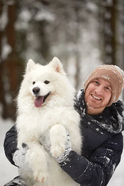 人間と犬は親友です。晴れた日には深い雪の中で冬の雪の森の中を歩く男と犬. — ストック写真