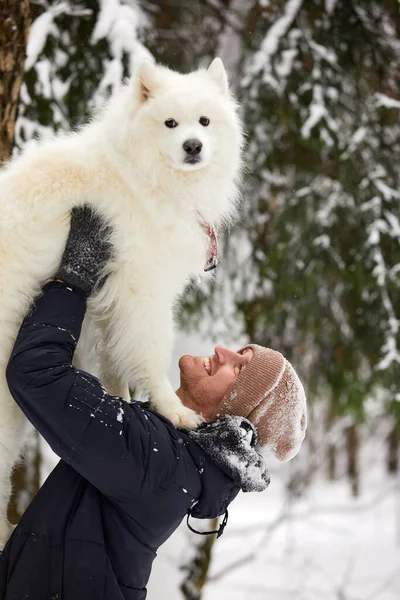 人間と犬は親友です。晴れた日には深い雪の中で冬の雪の森の中を歩く男と犬. — ストック写真