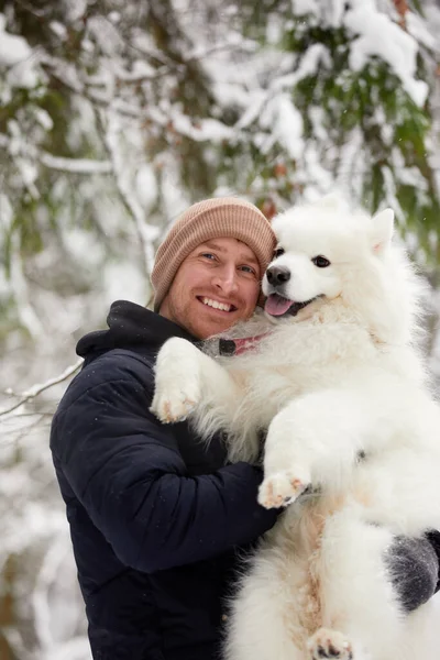 人間と犬は親友です。晴れた日には深い雪の中で冬の雪の森の中を歩く男と犬. — ストック写真