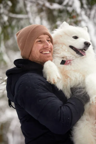 人間と犬は親友です。晴れた日には深い雪の中で冬の雪の森の中を歩く男と犬. — ストック写真