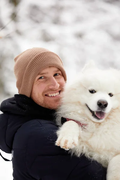 人間と犬は親友です。晴れた日には深い雪の中で冬の雪の森の中を歩く男と犬. — ストック写真