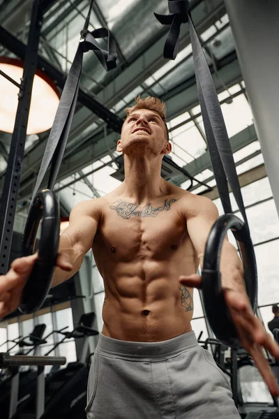 Muskeltraining junger Mann beim intensiven Cross-Fit-Training im Fitnessstudio an den Ringen. — Stockfoto