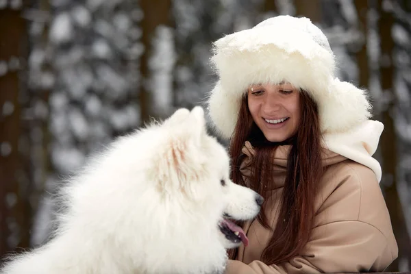 冬の幸せな若い女性,彼女の腕の中で保持し、彼女のペット犬と雪の中で遊ぶ — ストック写真