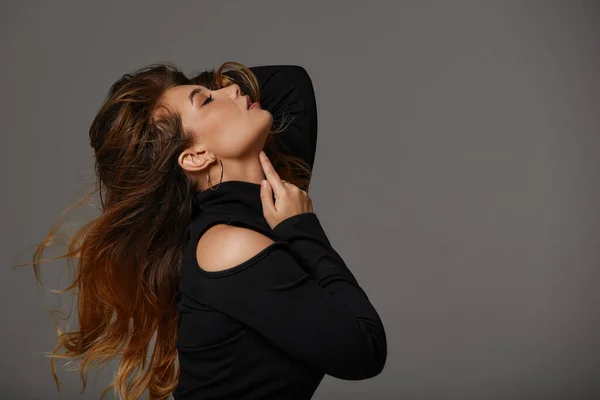 Retrato de moda de mujer modelo agradable con pelo largo y saludable en vestido negro sobre fondo gris, hermoso perfil facial —  Fotos de Stock