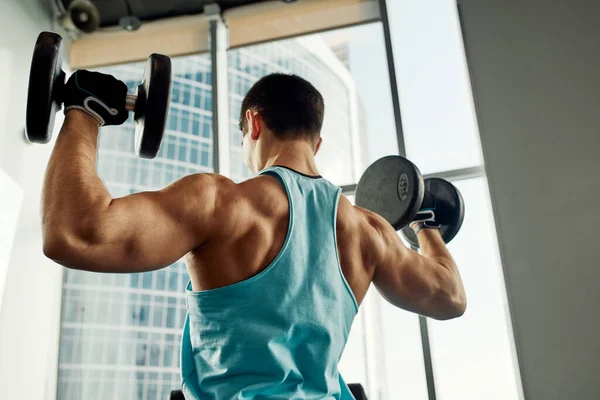 El atlético sacude los bíceps con la mancuerna en las manos. concepto de estilo de vida saludable —  Fotos de Stock