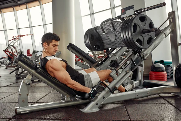 Training legs in the simulator, the athlete works with his legs on the simulator, working out the muscles on the legs