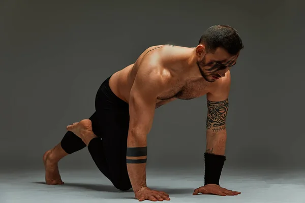 Instructor de fitness de instinto animal deportista mostrando su increíble flexibilidad con un movimiento de flujo animal en el estudio sobre un fondo gris —  Fotos de Stock