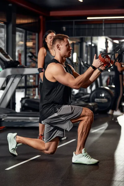 一个男人在体育馆里用模拟器锻炼他的胳膊和胸部，为不同的肌肉群做运动。发现动机，运动生活方式，健康，运动身体，身体积极。薄膜颗粒. — 图库照片