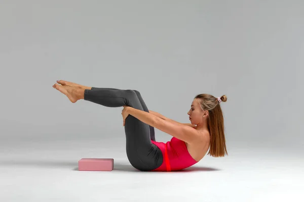 Yoga with brick. Slim athletic caucasian woman practice yoga pose using pink block in fitness studio indoor