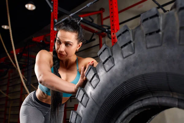 Fit female athlete working out with a huge tire turning and flipping in the gym. Woman exercising with big tire Stock Image Everypixel