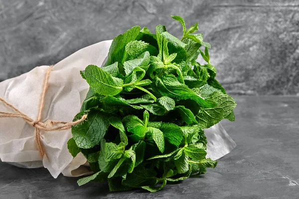 A bunch of mint, spearmint, peppermint tied with twine on a gray background. mint-flavored leaves. Mint bunch