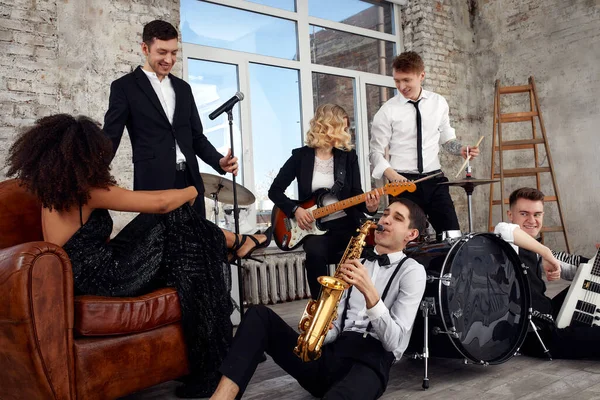 Repetition of multi ethnic jazz band in loft. Bass guitar player, electric guitar player, saxophonist and drummer at loft. Jazz music and jam session concept. passion for music and youth culture.