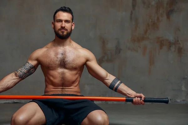 An experienced fighter, stands in a fighting posture with a fighting bamboo stick. Sport banner.