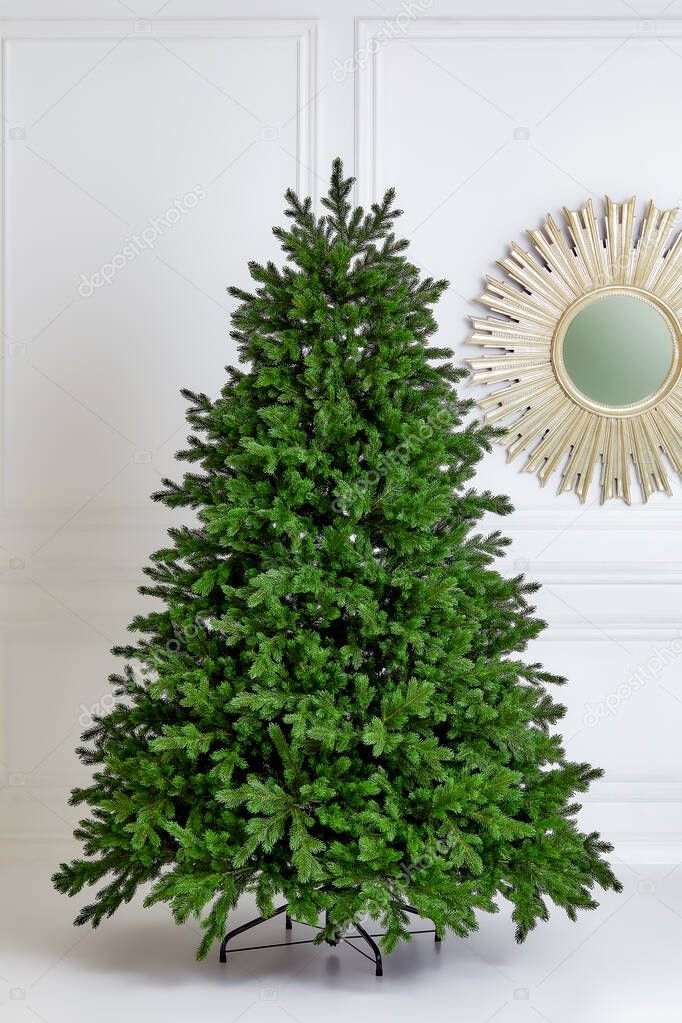 Artificial Christmas green tree without decorations on a metal stand isolated on a white background