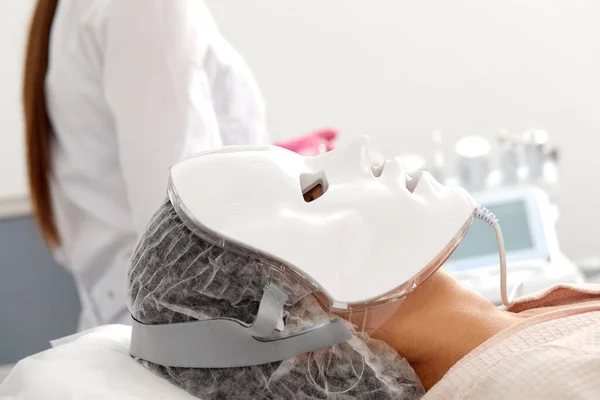 LED light anti-aging mask for facial skin care in a spa slow motion. A woman lies on a couch in a special mask. Modern technologies of beauty and health