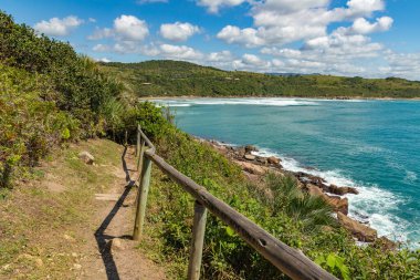 Sahile doğru kayalar ve bitki örtüsüyle Praia do Rosa, Imbituba, Santa Catarina, Brezilya