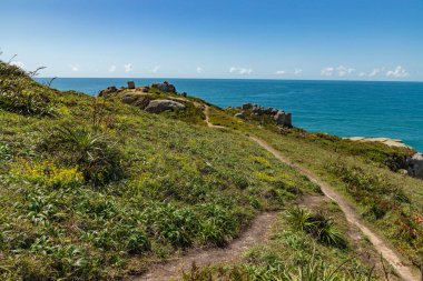 Sahile doğru kayalar ve bitki örtüsüyle Praia do Rosa, Imbituba, Santa Catarina, Brezilya