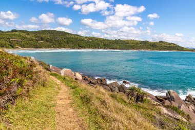 Sahile doğru kayalar ve bitki örtüsüyle Praia do Rosa, Imbituba, Santa Catarina, Brezilya
