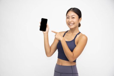 Beyaz arka planda cep telefonu uygulamasını gösteren ya da sunan Asyalı sporcu kadının portresi