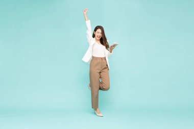 Çekici Asyalı güzel iş kadını ayağa kalktı ve ellerini kaldırdı mutluluktan kollarını kaldırdı ve hesap makinesini yeşil arka planda izole etti heyecanlı kadın kazanan konsepti