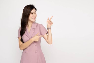 Genç Asyalı kadın gülümsüyor ve beyaz arka planda izole edilmiş boş kopya alanına işaret ediyor