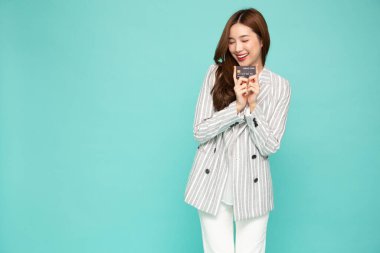 Genç, güzel Asyalı bir kadın gülümseyerek, göstererek, yeşil arka planda ödeme yapmak için kredi kartı sunarak.