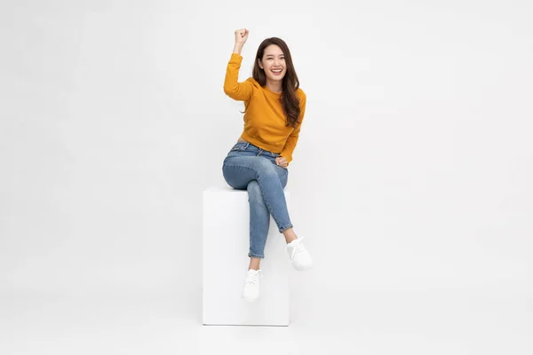 迷人美丽的亚洲女人坐在白盒上 双手高举幸福的臂膀 充满激情的女性和获奖者的成功理念 — 图库照片