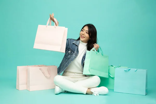 Asian Woman Holding Shopping Bags Sitting Floor Isolated Green Background — 스톡 사진