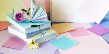 Üzerinde çiçekler, kalemler, not defterleri olan kitaplar, renkli renkli renkli renkli kağıtların arka planında, öğrenim kavramı, eğitim, okula dönüş. 