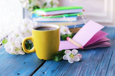 Bir fincan kahve, boş defter, elma ağacı çiçekleri ve bir yığın kitap, tahta pencere eşiğinde, bahar tatili konsepti, romantik ruh hali.