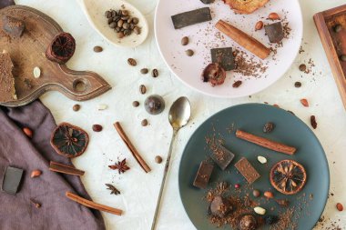 Siyah ve sütlü çikolata, tatlılar, kurutulmuş narenciye meyveleri, kahve çekirdekleri ve baharatlar masanın üstünde, üst manzara, ev yemeği, tatlı yiyecekler.